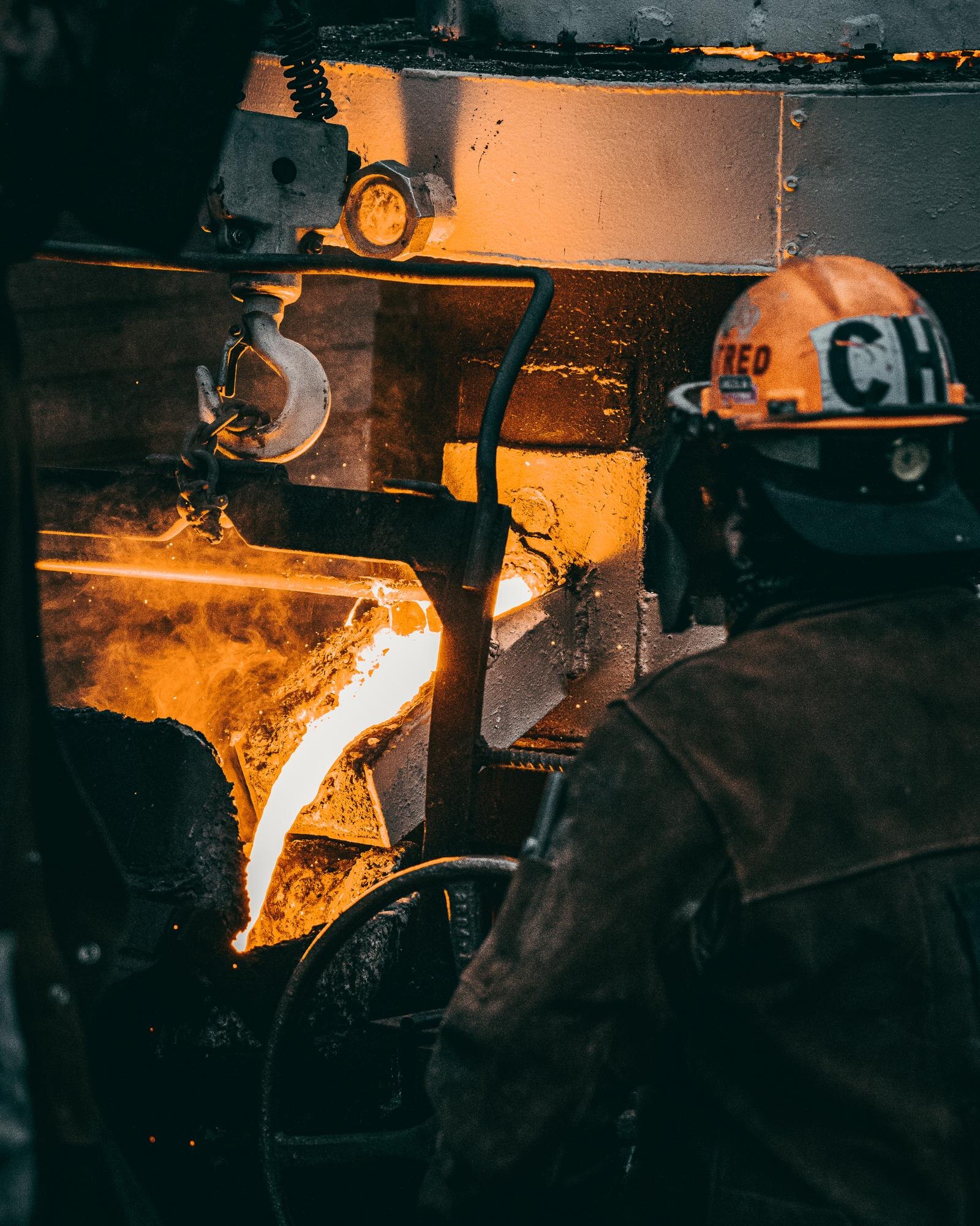 Trabalhador em ambiente industrial monitorando o vazamento do metal líquido durante as etapas do processo de microfusão (cera perdida) em uma fundição.