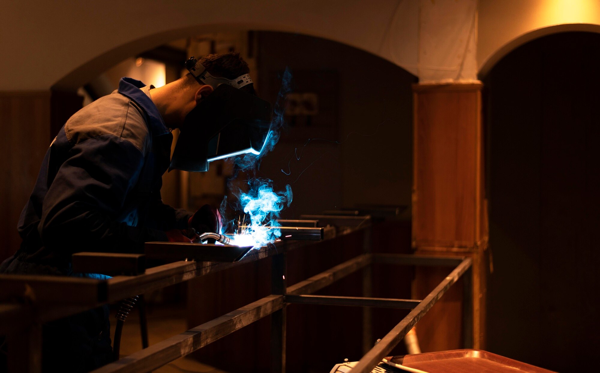 Profissional realizando soldagem em ambiente industrial, representando a aplicação de tratamentos térmicos e superficiais para peças fundidas que garantem resistência e acabamento de alta qualidade.