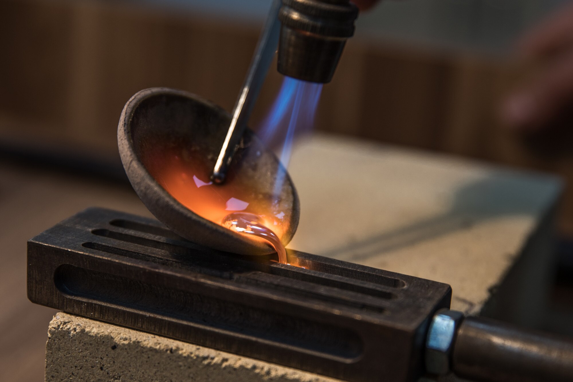 Detalhe do vazamento de metal aquecido em molde durante processo de fundição para projeto industrial, com controle térmico e foco na formação precisa da peça em aço.